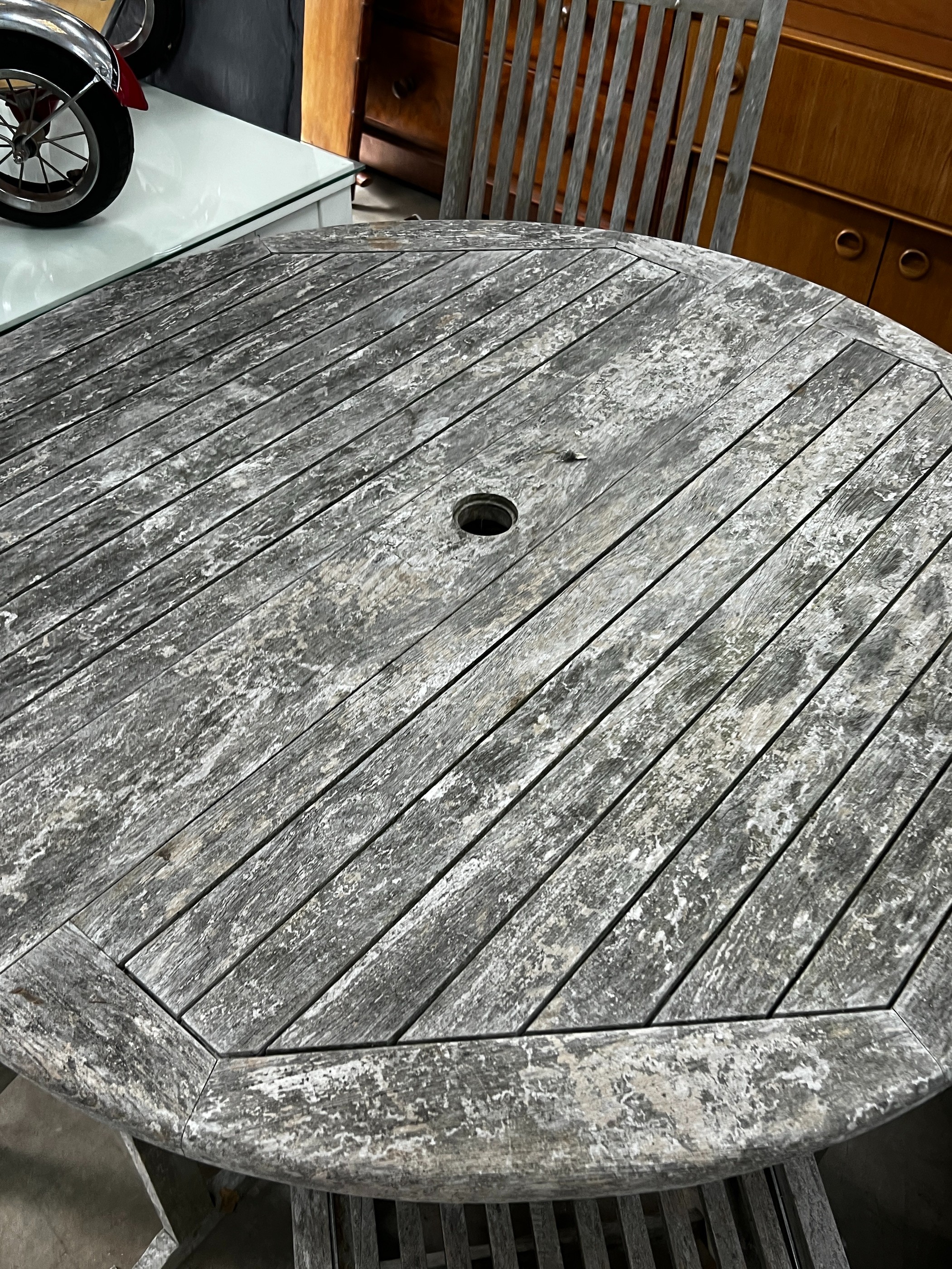 A Jo Alexander circular weathered teak folding garden table, diameter 120cm, height 75cm and four chairs *Please note the sale commences at 9am.